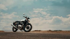 A Royal Enfield motorcycle parked on a scenic road with a clear blue sky backdrop.